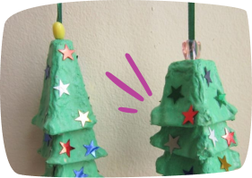 Two handmade Christmas trees crafted from green painted egg cartons, decorated with colorful star stickers and topped with small beads.