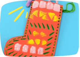 A colorful handmade Christmas stocking craft decorated with orange, yellow, green, and pink painted patterns on cardboard.