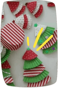 Colorful Christmas trees made from folded cupcake liners in red, white, and green patterns, arranged on a white surface as a holiday craft activity.