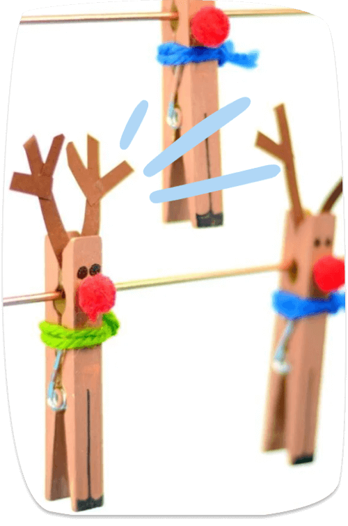 Cute reindeer Christmas ornaments handmade from wooden clothespins, decorated with pom-pom noses, yarn scarves, and stick antlers.
