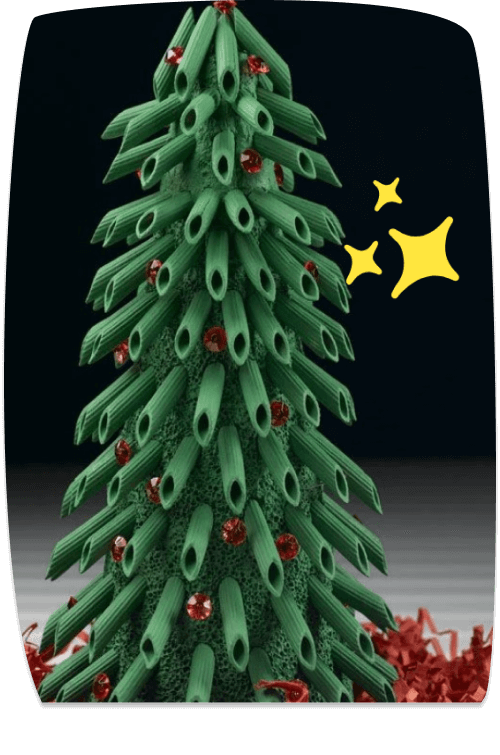 A decorative Christmas tree made from green pasta tubes, adorned with red gemstone ornaments and red tinsel at the base, with sparkle emojis beside it.