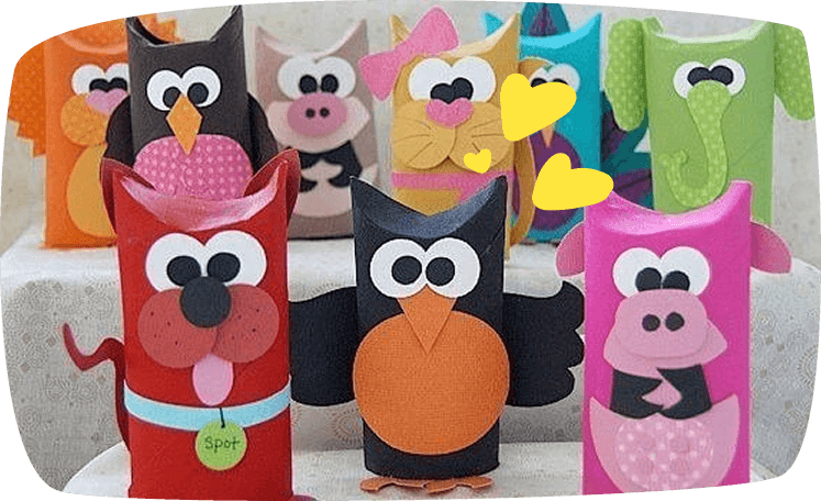 A collection of colorful animal finger puppets or decorations made from cardboard toilet paper rolls, featuring an owl, dog, pig, and other creatures decorated with paper cutouts.