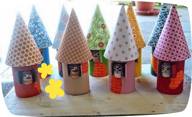 A collection of handmade birdhouses crafted from cardboard tubes and decorated with patterned paper cones as roofs, each featuring a small owl figurine peeking through the opening.
